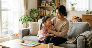 リビングで子どもと笑顔で過ごす母親のイメージ