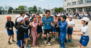 校庭で子供たちに囲まれて笑顔でハイタッチをするサッカー選手のイメージ写真