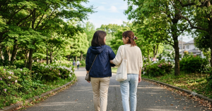 仲良くおしゃべりをしながら歩く若い女性と母親の後ろ姿
